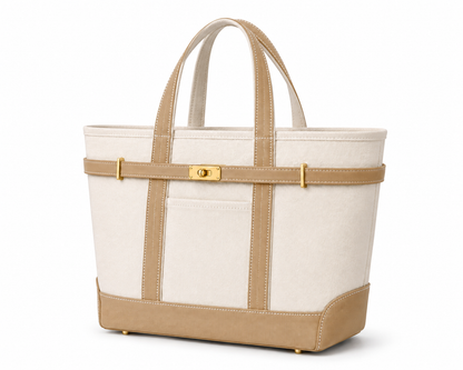 A structured canvas tote bag in off-white and tan with gold-tone hardware, featuring dual top handles, a front pocket, and a horizontal strap across the middle.