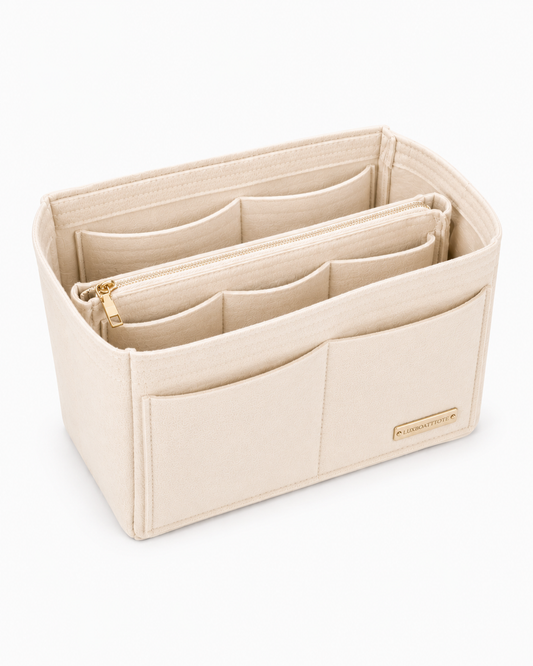A beige fabric organizer insert with multiple compartments and a gold zipper, shown on a clean white background.