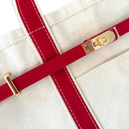 Close-up of a red strap with gold hardware on a white background